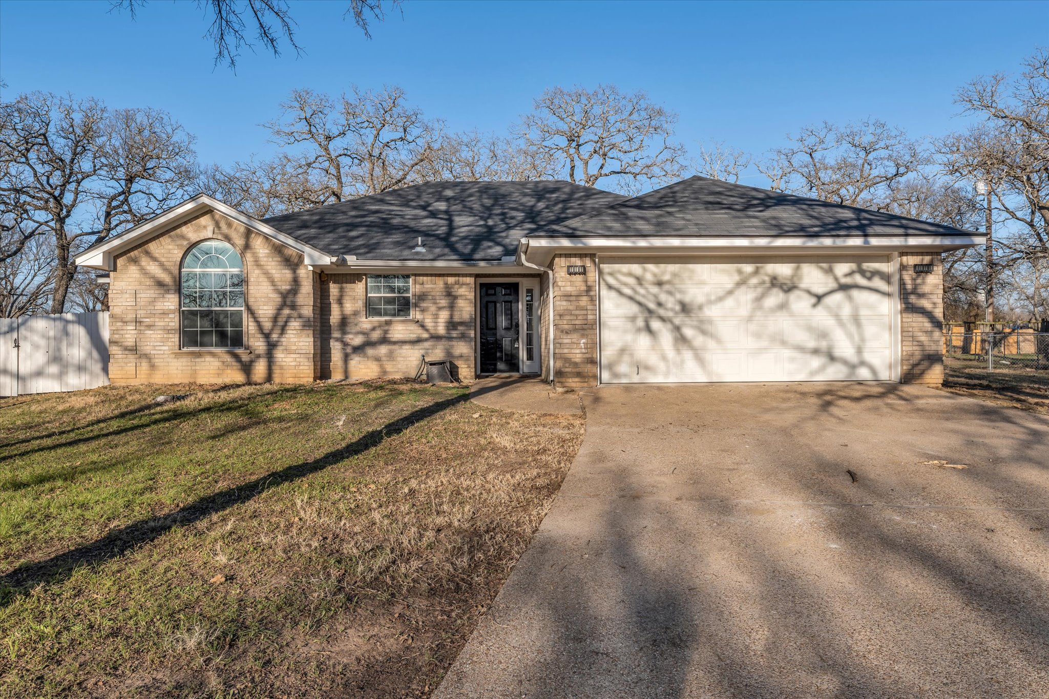 Front of home featuring brick siding, driveway, a garage, and roof with shingles