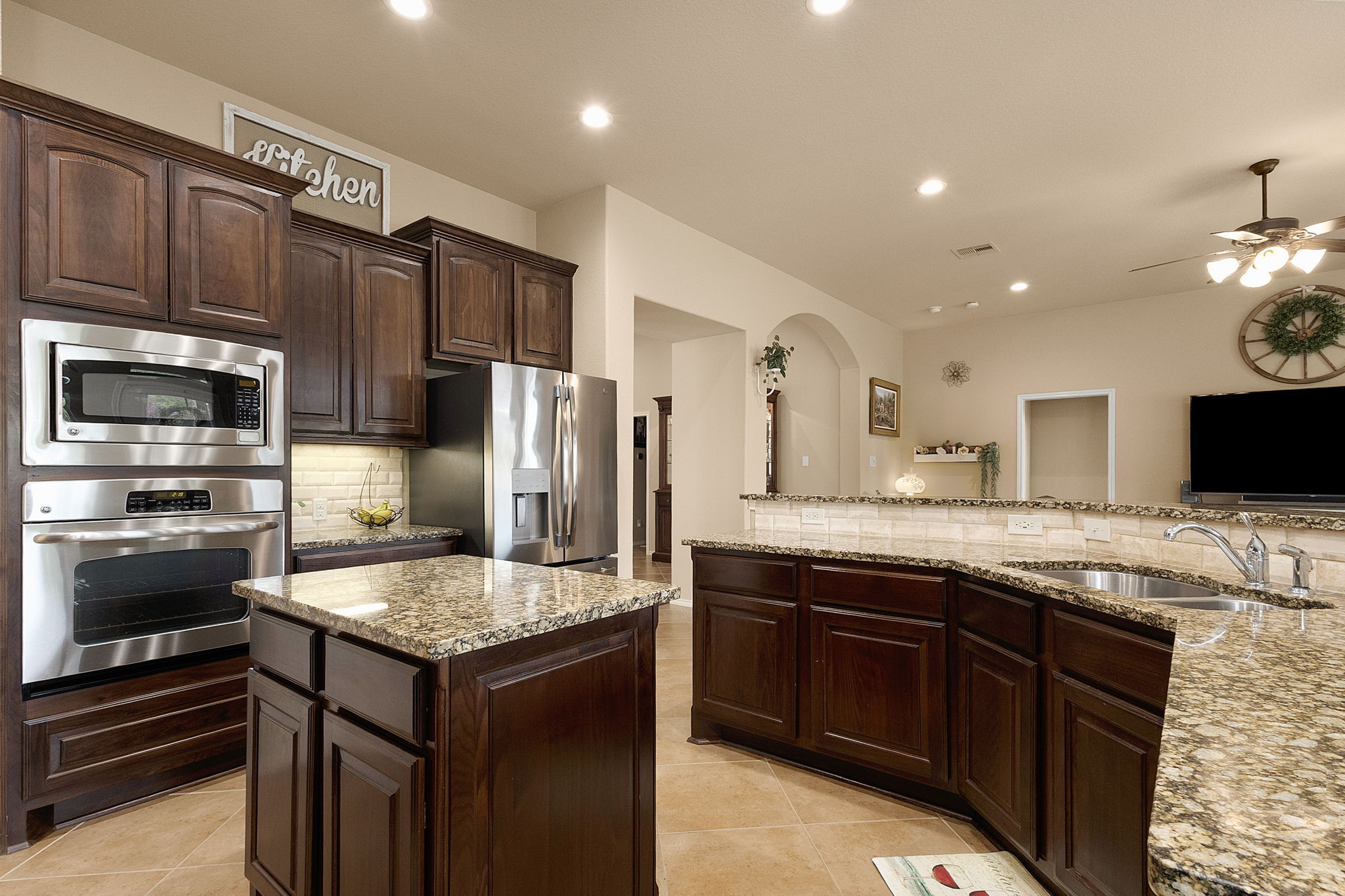 Kitchen with dark wood finish cabinetry, tasteful backsplash, stainless steel appliances, a center island, and light counters