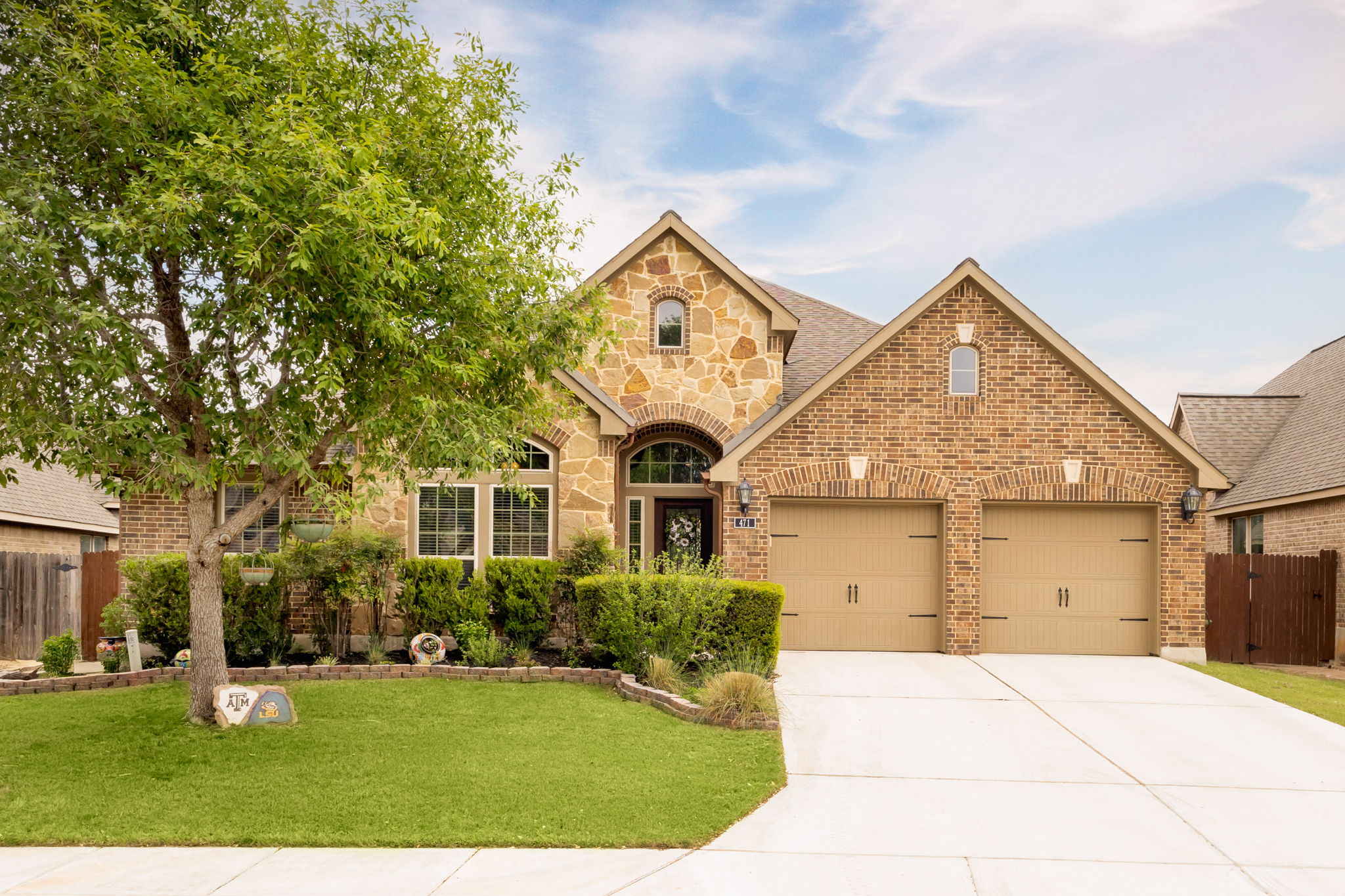 View of front of home with stone siding, brick siding, concrete driveway, and an attached garage