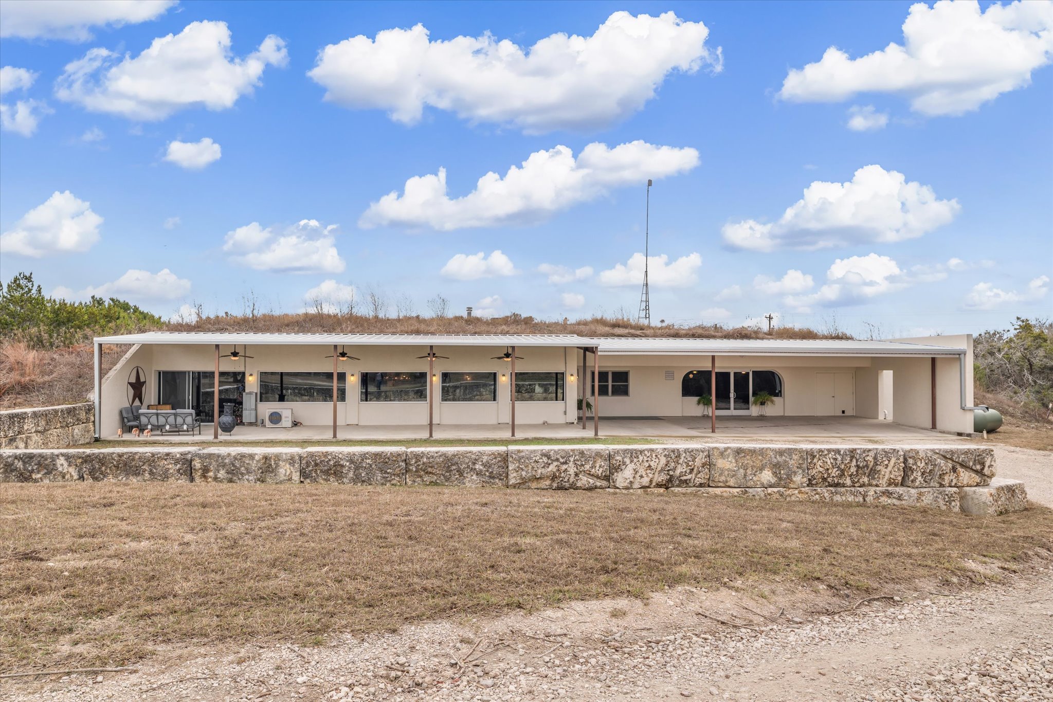 Front view of property featuring a patio area, ceiling fan, and a carport