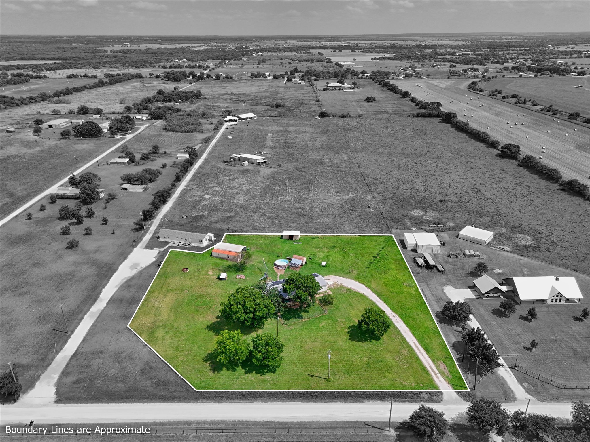 Expansive rural property featuring multiple structures, verdant green space, a long driveway, and mature trees